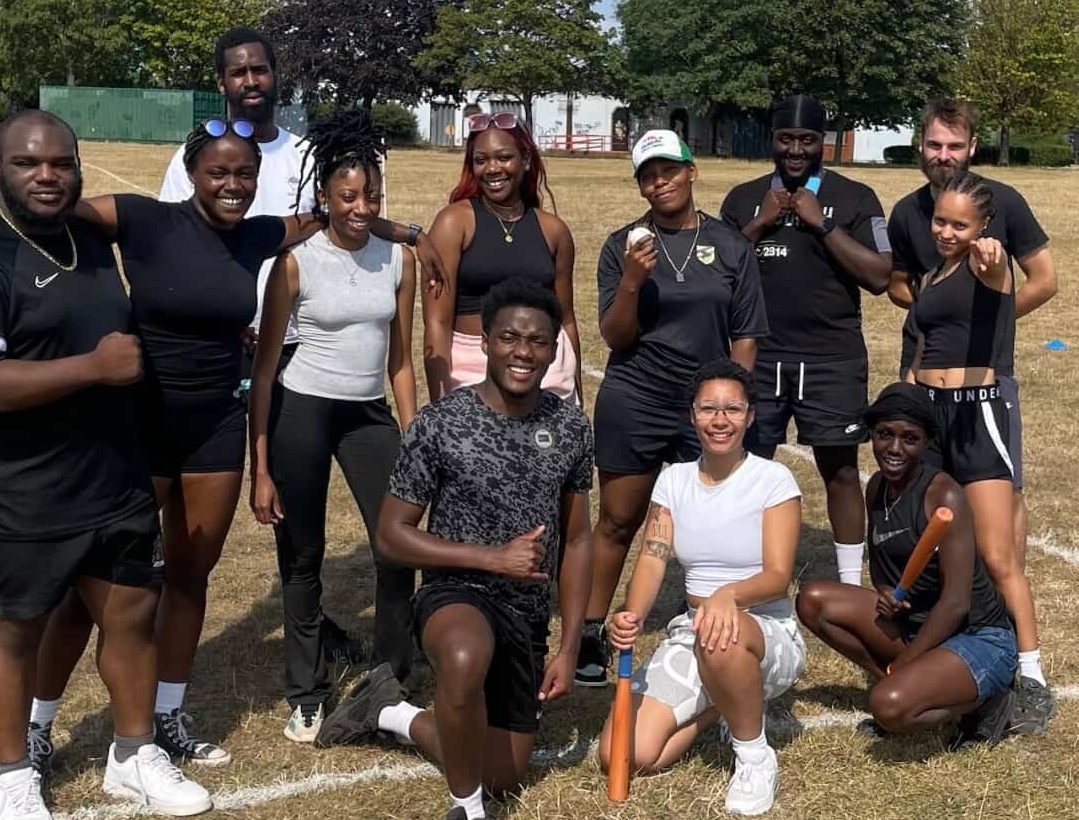A diverse group of young adults, posing for a team photo in the park.