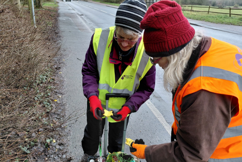 Two litter pickers inspecting stolen shopping tags found amongst collection.